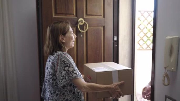 老年白人女性养老金领取者在他家门口收到快递员的邮政包裹。