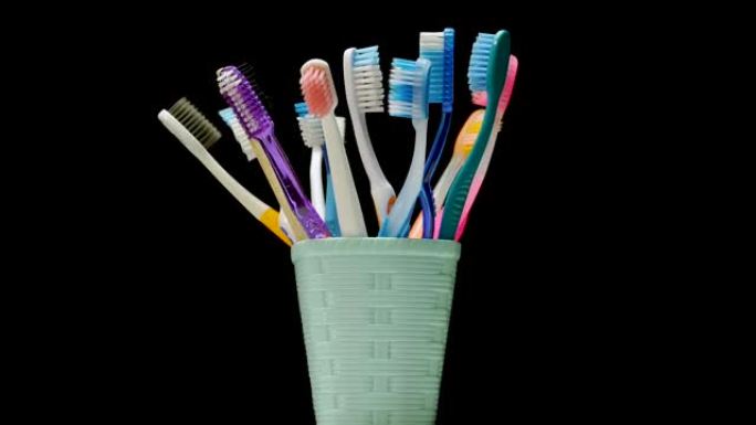 篮子里的许多牙刷在黑色背景上旋转。护理牙齿，五彩牙刷