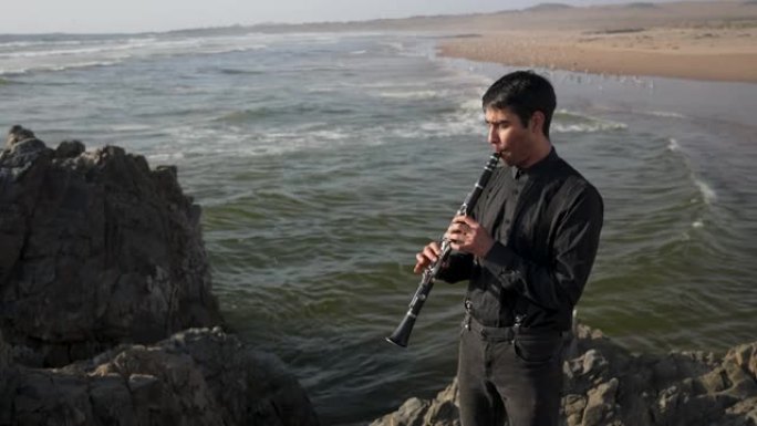 年轻的音乐家在海上的岩石上演奏单簧管，背景是海浪和海滩