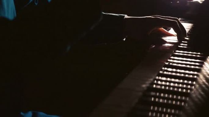钢琴家在音乐会上在舞台上演奏美丽的三角钢琴。特写。男性手演奏三角钢琴的镜头。男人用手指触摸钥匙。