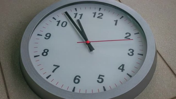 现代灰色挂钟的特写时间流逝，钟面上有数字。选择性地关注数字5或5点。秒针经常超过分钟。时间过得很快