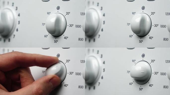 在洗衣机上设置温度的手的特写镜头