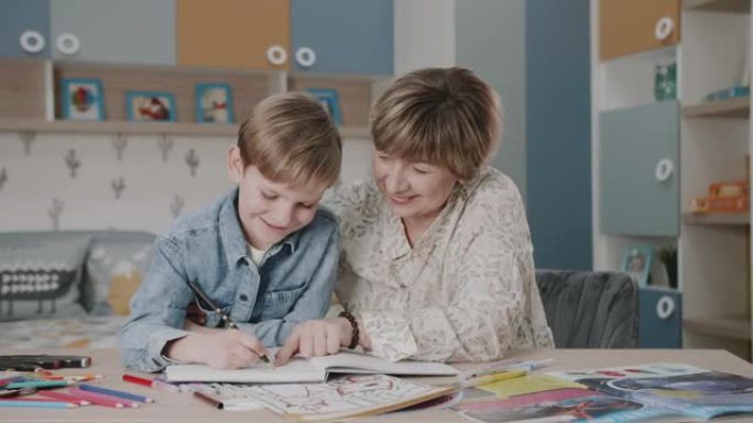 奶奶和孙子正在做作业。一个幸福家庭的肖像。在家学习。教学。祖母和孙子笑了。框架中可爱的情感。一个家庭