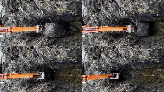 在冬季，挖掘机的铲斗从地面上取土的垂直镜头。宽镜头