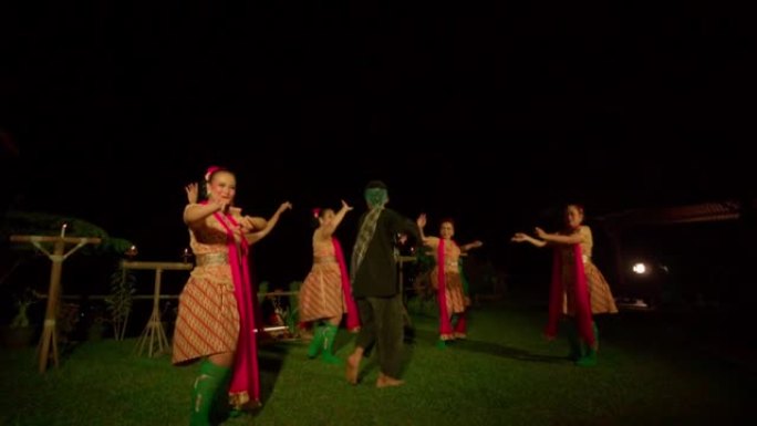 巴厘岛妇女跳舞庆祝仪式，而一个男人在舞台上的舞者之间浪费金钱