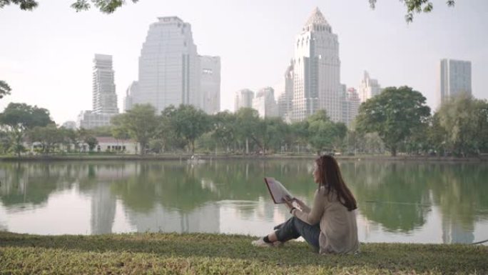 亚洲妇女很高兴通过早上在城市公园读书来放松身心，人们在城市自然环境中放松身心。