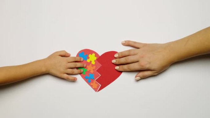 自闭症儿童的支持和意识概念。世界自闭症日。妇女和儿童手中的两半心脏连接成一个整体