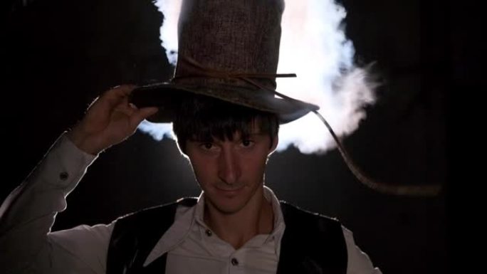 一个男炼金术士把一顶帽子戴在头上。蒸汽从帽子里冒出来。炼金术,魔法,神秘主义
