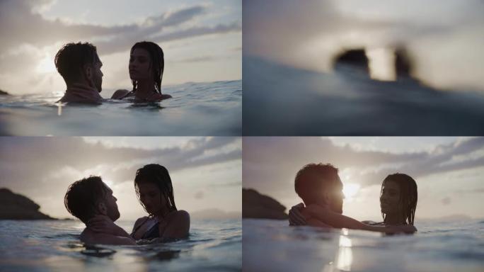 暑假浪漫的异性恋夫妇。在美丽的金色日落时在海里游泳。接吻
