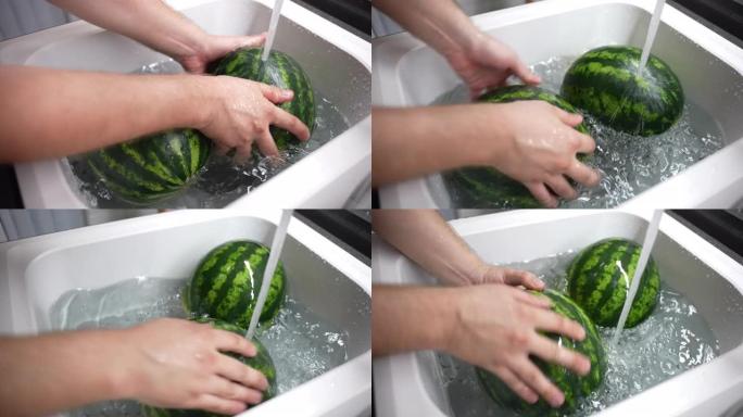 人用温水和可溶性苏打水在厨房水槽中清洗大圆条纹西瓜，以去除水果表面，土壤微生物和细菌中的工业化学添加
