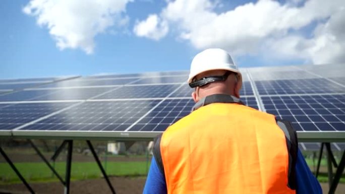 穿着特殊制服和防护头盔的男工人在太阳能电池板上固定。替代能源的维修和保养。