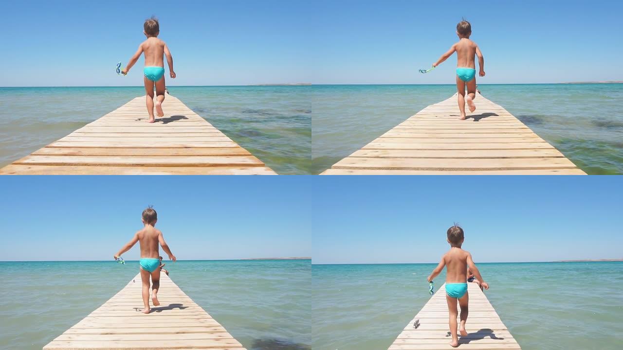 快乐的男孩，一个沿着海码头走向蔚蓝的大海的孩子，慢动作。阳光明媚的夏日在碧绿的海和蓝天的岸边