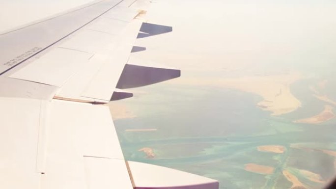 阿布扎比市郊区和沙漠的鸟瞰图，带有机翼背景窗口的河流。阿联酋荒芜的风景和机舱的飞机机翼景观。中东概念
