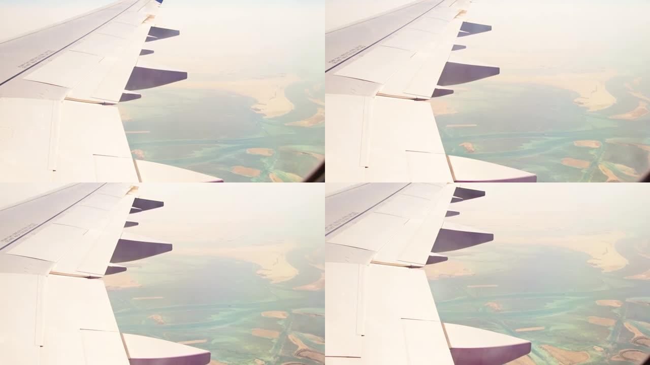 阿布扎比市郊区和沙漠的鸟瞰图，带有机翼背景窗口的河流。阿联酋荒芜的风景和机舱的飞机机翼景观。中东概念