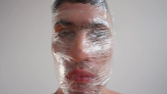 肖像，用保鲜膜包裹男性脸。塑料垃圾的概念问题