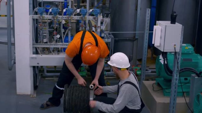 石化行业的两名员工正在地层水处理厂工作，扭动保护性呼吸器的软管。工厂工作