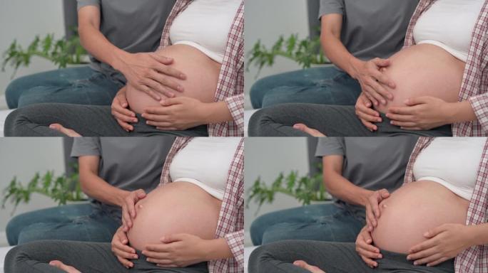 父亲用手触摸孕妇的肚子。丈夫和妻子用手触摸来感觉婴儿。家庭爱情概念。