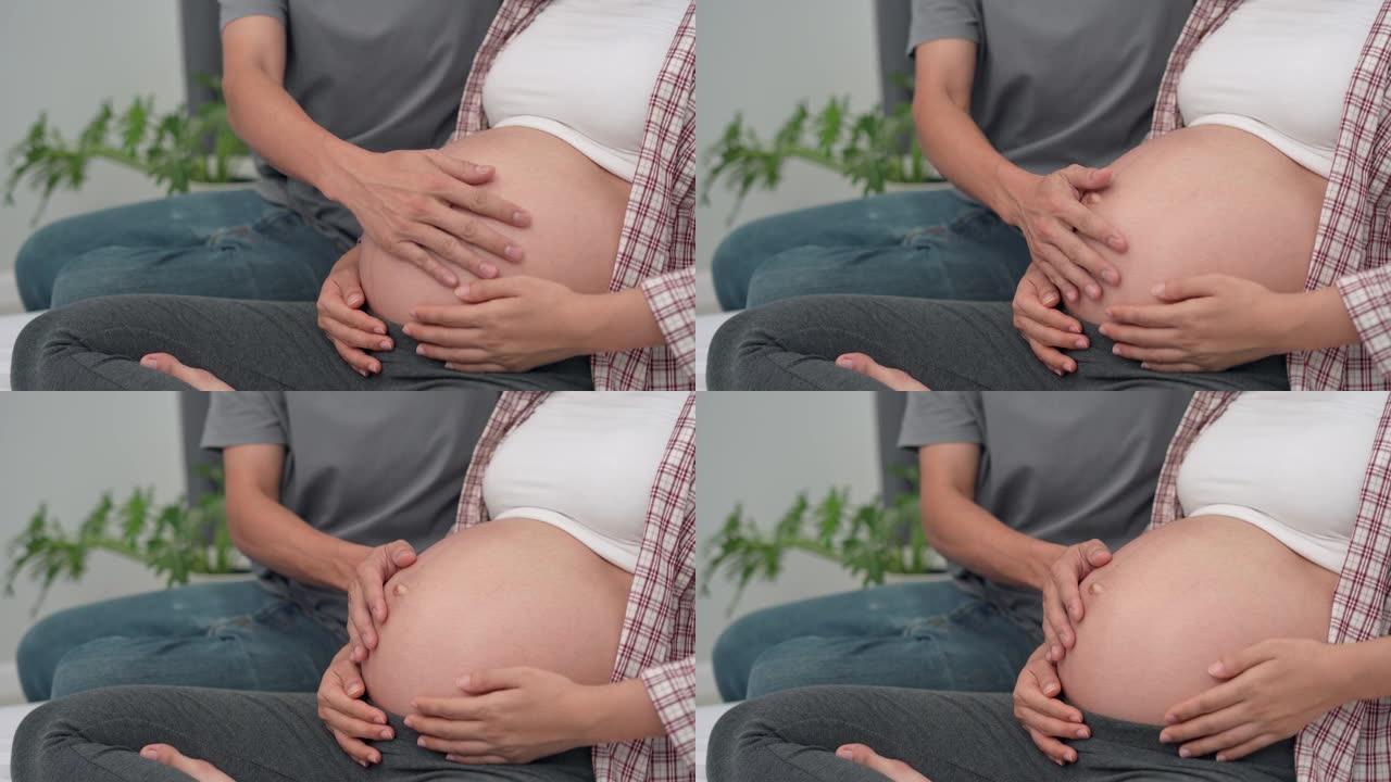 父亲用手触摸孕妇的肚子。丈夫和妻子用手触摸来感觉婴儿。家庭爱情概念。