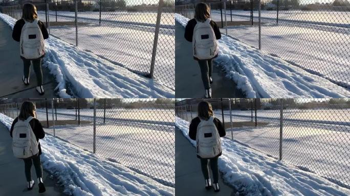 年轻女孩在冬天独自一人上学的时候看着她身后