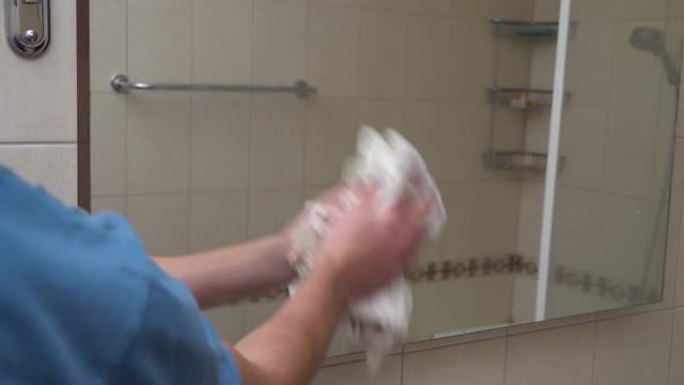 男人在浴室用抹布擦拭镜子