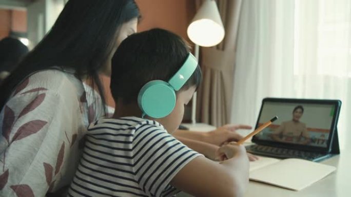 亚洲妈妈在家上学期间向孩子儿子教授和解释家庭作业以进行在线学习，概念在线学习
