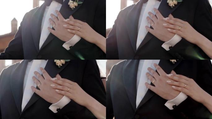 新婚夫妇手指上的金色结婚戒指，幸福的新娘在婚礼后抚摸着她心爱的新郎的手，结婚戒指象征着两个相爱的人之