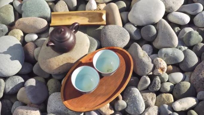 木托盘上两个空杯子的特写镜头，一个棕色茶壶，