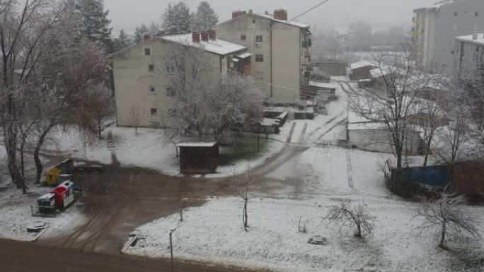 城市降雪。大片白色雪花从多云的天空落下。巴尔干半岛的天气预报。唐楼和树木被雪覆盖。