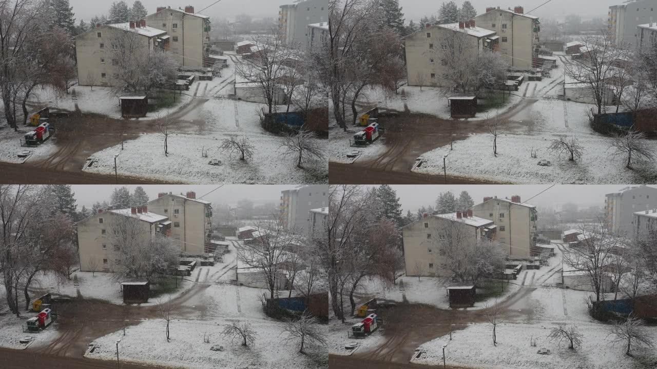 城市降雪。大片白色雪花从多云的天空落下。巴尔干半岛的天气预报。唐楼和树木被雪覆盖。