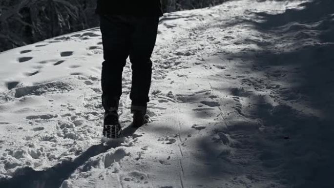 男人的腿在雪地上行走，脚印在高清
