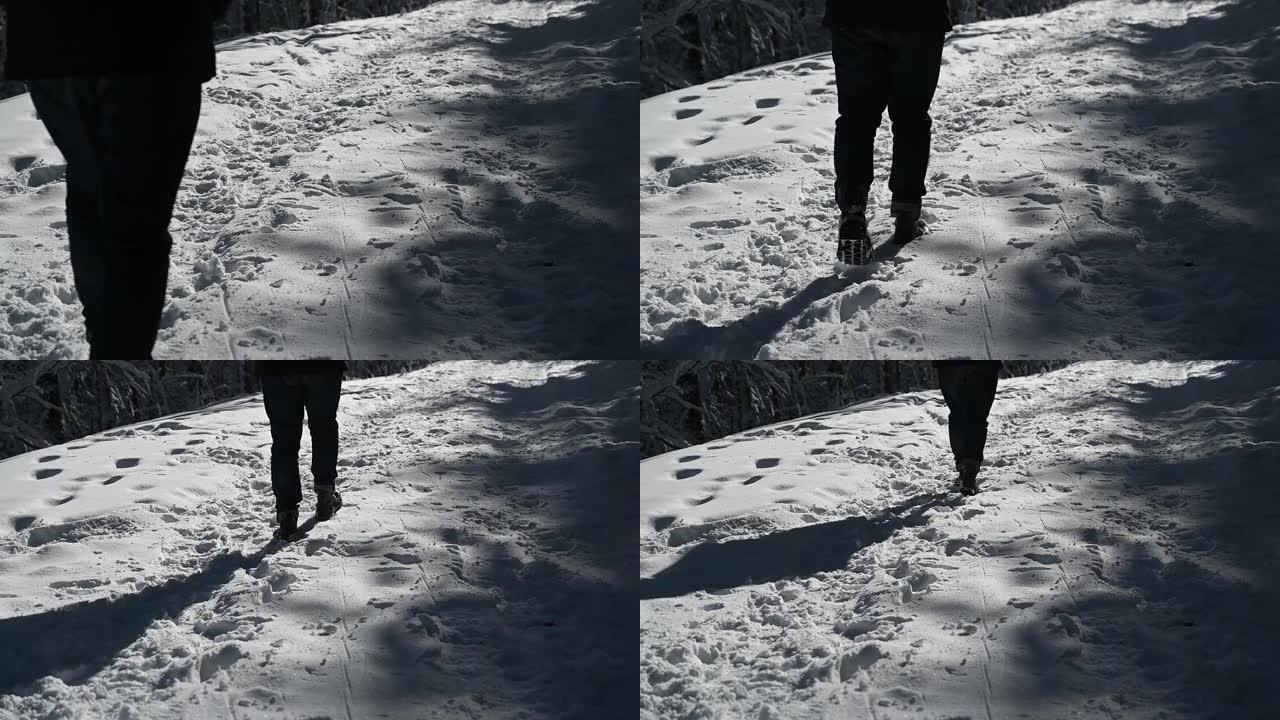 男人的腿在雪地上行走，脚印在高清