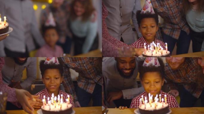 快乐的非洲裔美国青春期男孩在生日蛋糕上吹蜡烛与家人庆祝