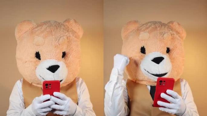 带熊面具的人在黄色背景上使用手机。社交媒体的垂直视频格式视图屏幕