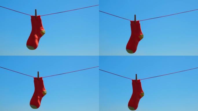 在对抗蓝天的绳索上悬挂着一只被遗忘的丢失的橙色袜子。家务的概念。软焦点