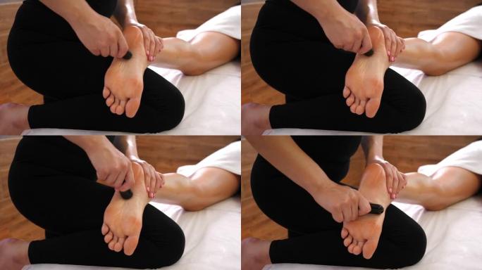 温泉沙龙中的热石按摩疗法为年轻女子腿部和脚部