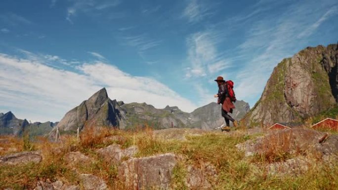 带着红色背包的女旅行者潮人在令人惊叹的山脉和山谷景色中向前走。