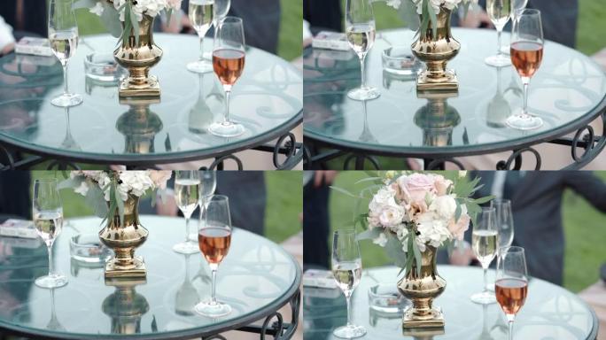 优雅的公司派对在令人惊叹的花园里，有圆形玻璃桌子和鲜花花束，同事放松，喝独家酒，聊天和享受派对。周末