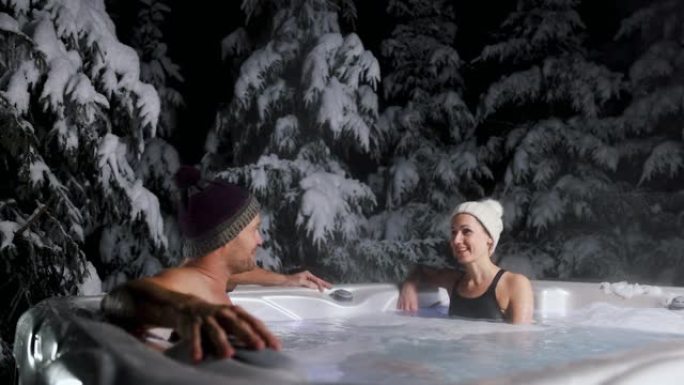 夫妇在冬季水疗度假村的室外热水浴缸中放松