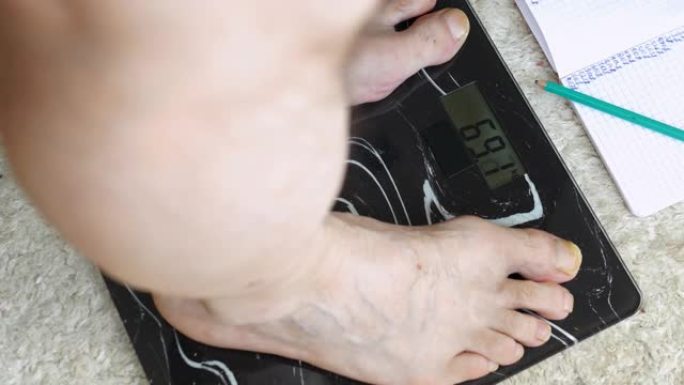 人的体重控制，男性老年人的腿站在地磅，68.8千克人，肥胖和超重的人。