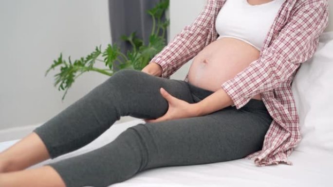 孕妇腿部抽筋，按摩减轻疼痛。抽筋是孕妇的常见症状。孕妇的概念症状。