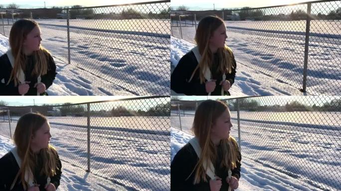 8-9岁的女孩在雪中沿着链节围栏从学校走回家