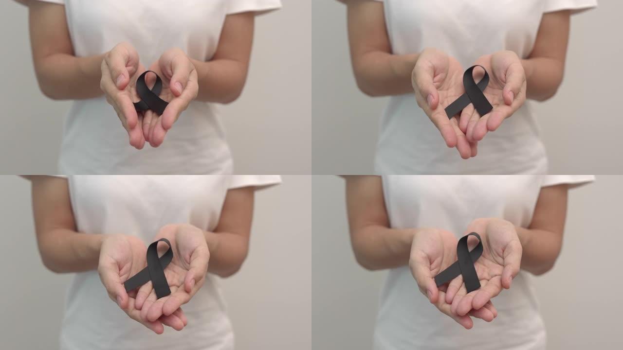 手持黑素瘤和皮肤癌黑丝带的妇女，疫苗伤害宣传月，悲伤和安息。保健和种族主义概念