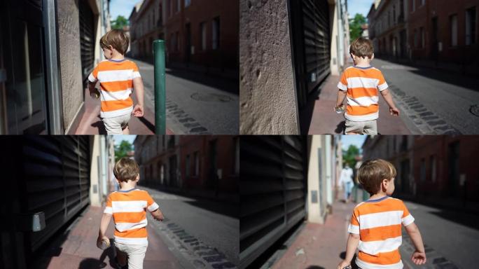 一个小男孩走在城市人行道上。阳光明媚的日子里，孩子在城市街道的户外散步。2岁的孩子走到外面
