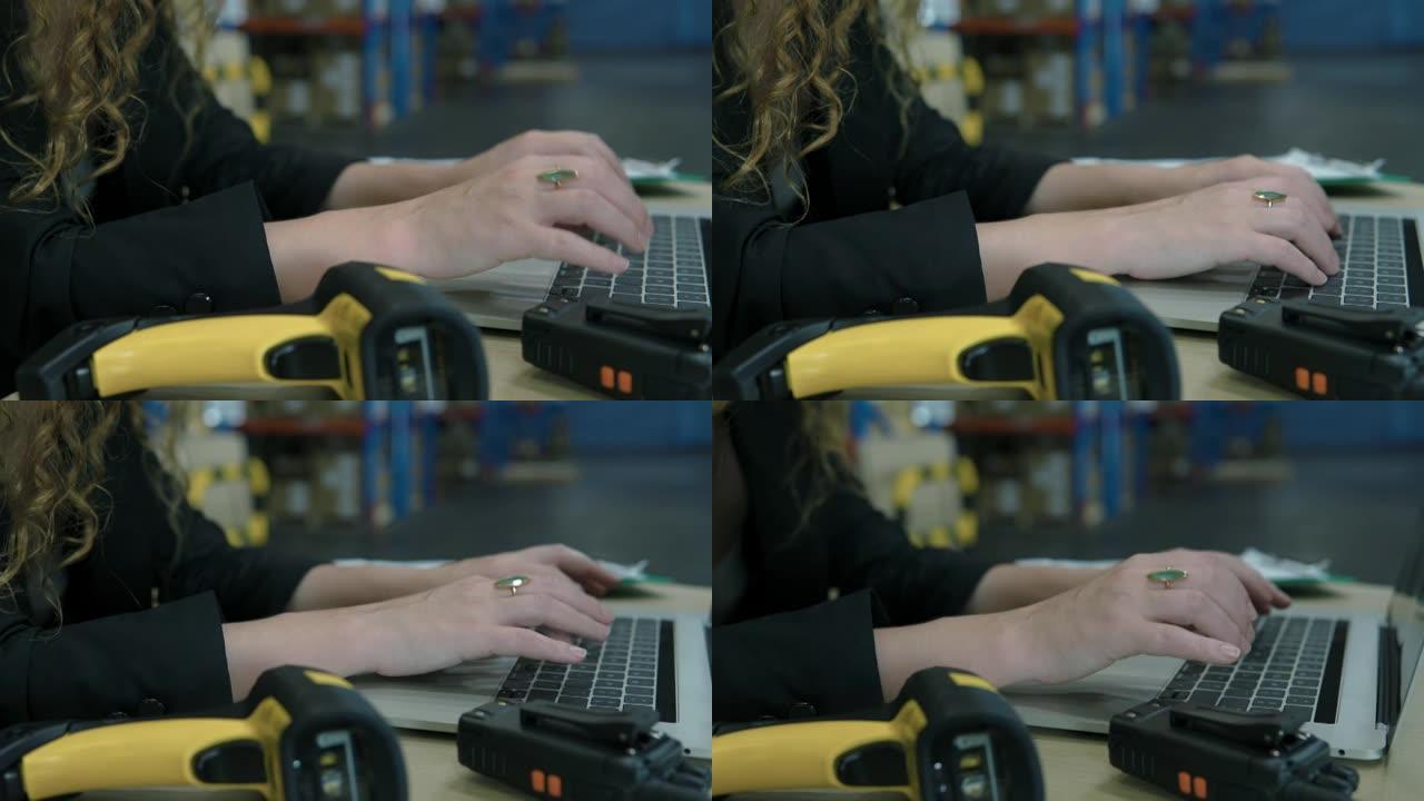 在仓库中使用笔记本电脑的女人的手的特写镜头。