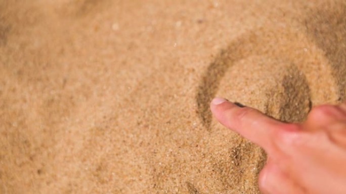 用手指在沙滩上画一颗心，是对海滩度假的热爱。海滩上的热黄色易碎沙子-海岸，度假村。