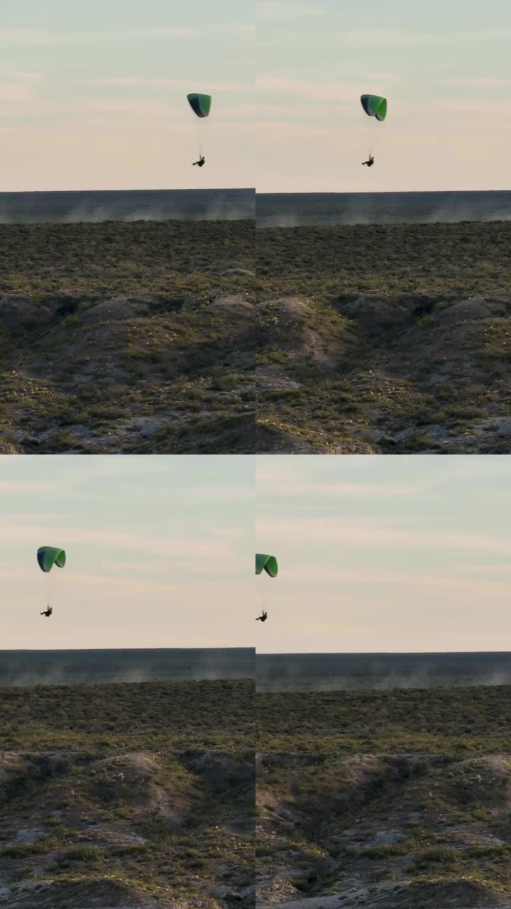 日落时在沙漠地区上空飞行的滑翔伞