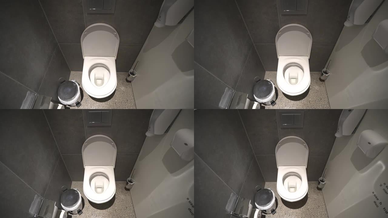 室内现代公共厕所在机舱内，配有干净的厕所、壁挂式盥洗室纸、垃圾处理器和消毒剂。浴室内部的白色陶瓷马桶