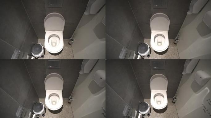室内现代公共厕所在机舱内，配有干净的厕所、壁挂式盥洗室纸、垃圾处理器和消毒剂。浴室内部的白色陶瓷马桶