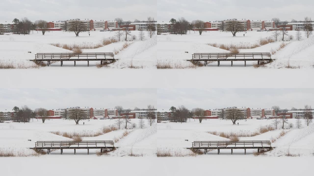 鸟瞰一个人走在积雪覆盖的田野里，后面有建筑物