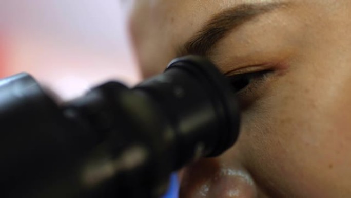 特写镜头，兽医女性的眼睛在显微镜下观察